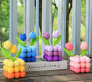 Colorful crocheted tulip sculptures on a wooden surface with a blurred natural background.