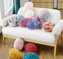 Colorful knitted yarn balls on a white chair and floor.