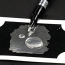 Fountain pen nib touching a black and white drawing of water droplets on a black background