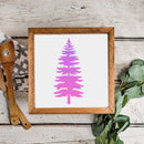Framed artwork with a pink tree design on a wooden surface with kitchen utensils and greenery.