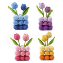 Set of four crocheted tulip flowers in blue, purple, pink, and orange on a white background.