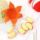 Crocheted orange and lemon slices on a book with red yarn in the background