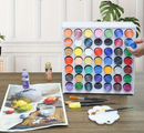 Set of watercolor paints with brushes and a painting on a table