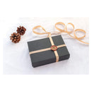 Black gift box with a gold ribbon and decorative seal on a white background