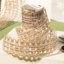 Spool of beige lace ribbon on a white surface with a blurred background