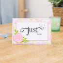 Greeting card with floral design and text 'just to say' on a wooden surface.