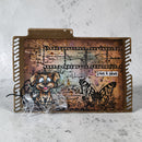 Decorative metal file folder with artistic design, butterfly, and text on a textured surface.