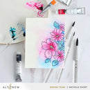 Floral watercolor painting on paper with art supplies including brushes and paint tubes.