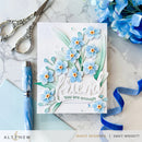 Card with blue flowers and 'friend, you are enough' text on a marble surface with scissors and pen.