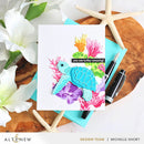 Colorful turtle card with floral elements on a wooden surface with flowers and starfish.