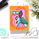 Card with turtle illustration and 'I believe in you' text on an orange background, surrounded by stationery items.