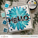 Card with blue floral design and 'HELLO' text, surrounded by craft supplies on a textured surface.