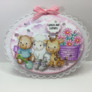 Decorative card with teddy bear, sheep, and giraffe illustration, surrounded by flowers and a pink bow.