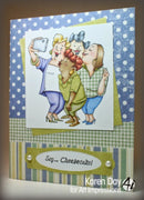 Card with illustration of three women taking a selfie and text 'Say... Cheesecake!' on a polka dot and striped border.