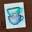Card with two coffee cups and text on a wooden surface with coffee beans.