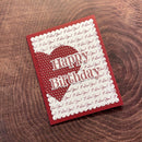 Red birthday card with heart design and 'Happy Birthday' text on a wooden surface