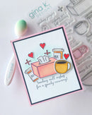 Card with illustrations of a tissue box, coffee cup, and medicine bottle with text 'Sending well wishes for a speedy recovery' on a crafting background.