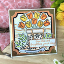 Decorative card with floral design and text on a wooden surface with flowers.