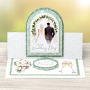 Wedding card with a couple under a floral arch, text 'On Your Wedding Day' and 'Just Married', on a wooden surface.