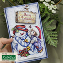 Christmas card with snowman and child design, held by a hand with greenery in the background.