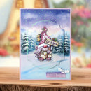 Christmas card with a snowy scene, tree, and 'Let it Snow' text on a wooden surface.