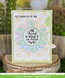 Greeting card with floral and butterfly design on a wooden block with plants in the background