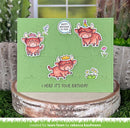 Green birthday card with cartoon bulls and decorative elements on a wooden block with plants in the background.