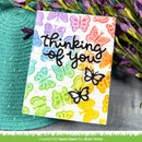 Card with colorful butterfly pattern and 'thinking of you' text, placed on a textured surface with flowers.