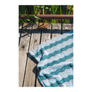 Crocheted blanket with a zigzag pattern on a wooden surface outdoors