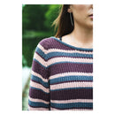 Person wearing a striped sweater with a blurred green background