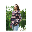 Woman wearing a striped sweater standing outdoors with greenery in the background