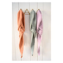 Three crochet Hooded Scarfs in orange, green, and pink hanging on a wooden rack against a white wooden panel background.