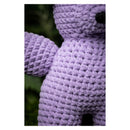 Close-up of a purple crochet teddy bear against a blurred green background