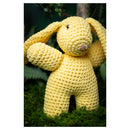 Yellow crocheted bunny toy on a green background