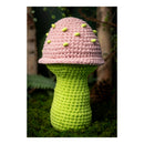 Crocheted mushroom toy with pink cap and green stem on grass