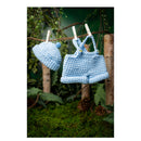 Crocheted baby outfit with hat and dress hanging on a clothesline against a natural background.