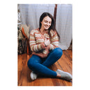 women wearing a cardigan sitting cross legged on a wooden floor