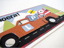 Decorative paper cutout of a car with road and traffic sign elements on a white background.