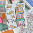 Colorful card with 'Le Petit Cafe' design and floral elements, surrounded by stamping supplies.