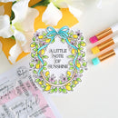 Decorative clear stamp with floral design and text 'A Little Note of Sunshine' on a white background with flowers and markers.