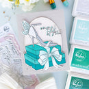 Card with high heel shoe and gift box design, surrounded by ink pads and stamp sets.
