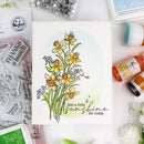 Card with floral design and text, surrounded by stamp set, ink pads, and decorative elements.