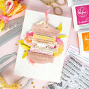 Handmade card with decorative elements and stamps on a pink background