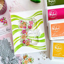 Card with floral design and text, surrounded by stamping supplies on a white surface