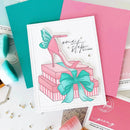 Card with high heel shoe on gift box design, surrounded by craft supplies.