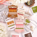 Collection of decorative gift tags with various designs and text on a white surface with flowers.