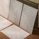 White embossed cards with geometric patterns on a brown surface