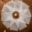 Set of white embossed cards on a brown surface with a small white flower.