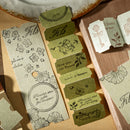 Set of decorative paper tags with floral designs and text on a wooden surface.
