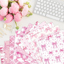 Pink stationery items with bow designs on a desk with flowers and a keyboard.